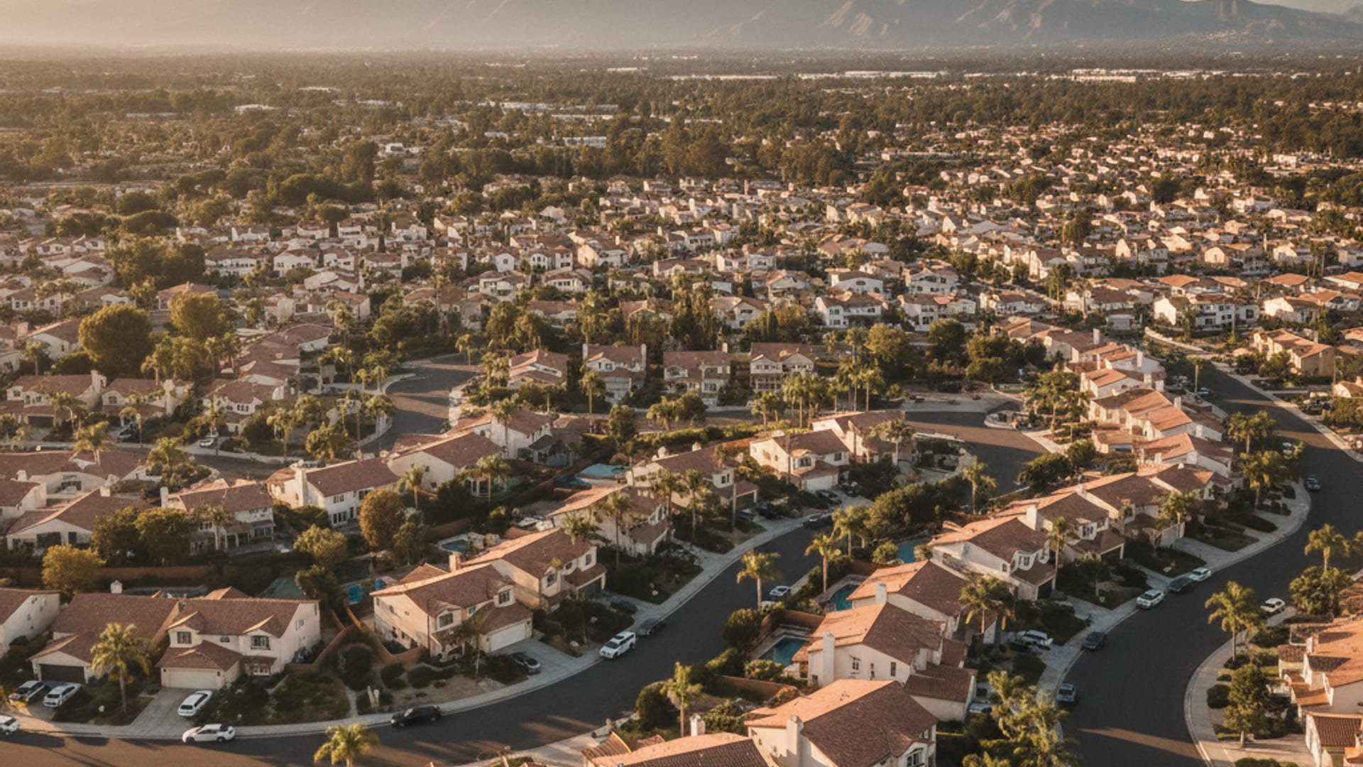 Aerial view of a San Diego County residential neighborhood with stucco homes and tile roofs in warm afternoon light
